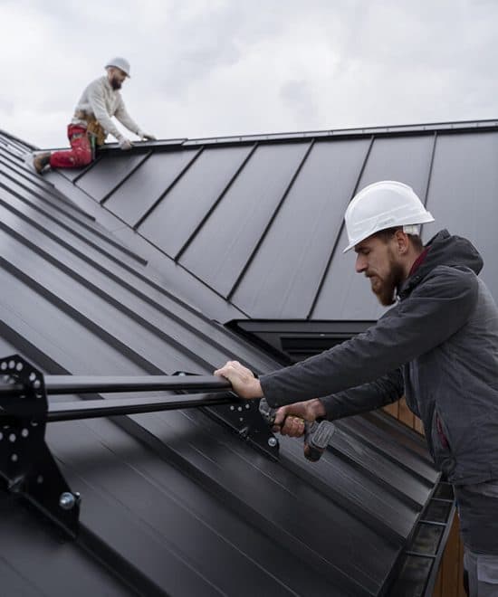 Construction workers installing metal standing seam roof with rail system